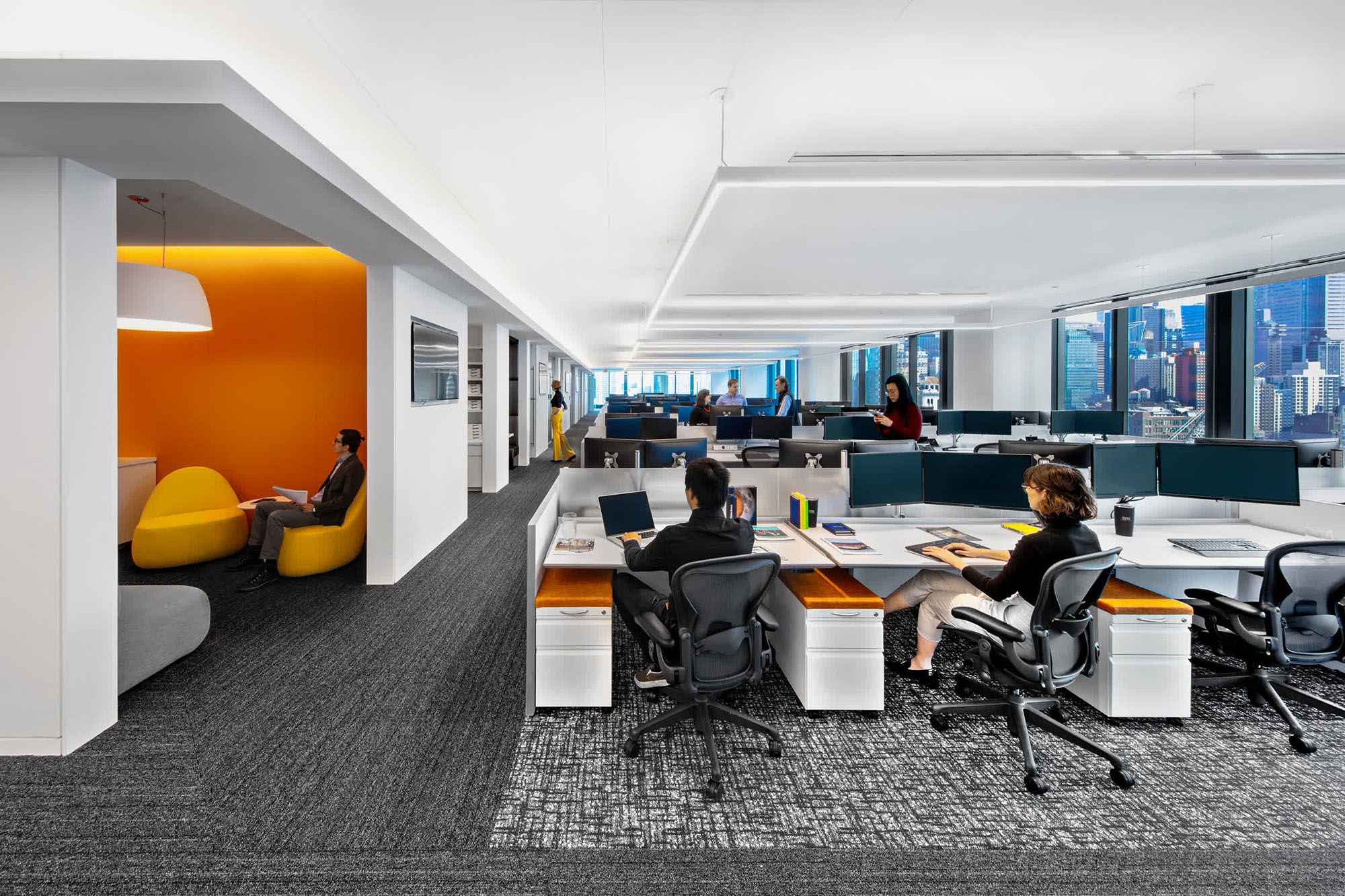 trading floor office with employees in formal clothes and orange furniture tops